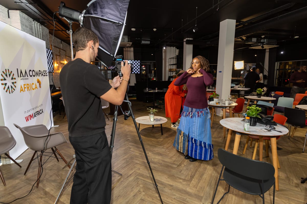 Alexander filming an interview against a WIM Africa banner at a corporate event.