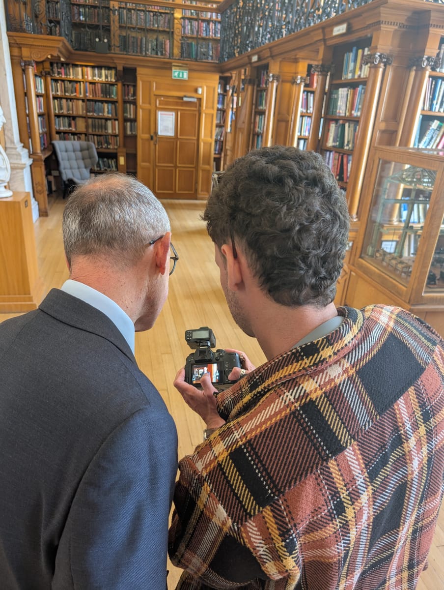 Reviewing footage on the camera with a client in a grand panelled library.