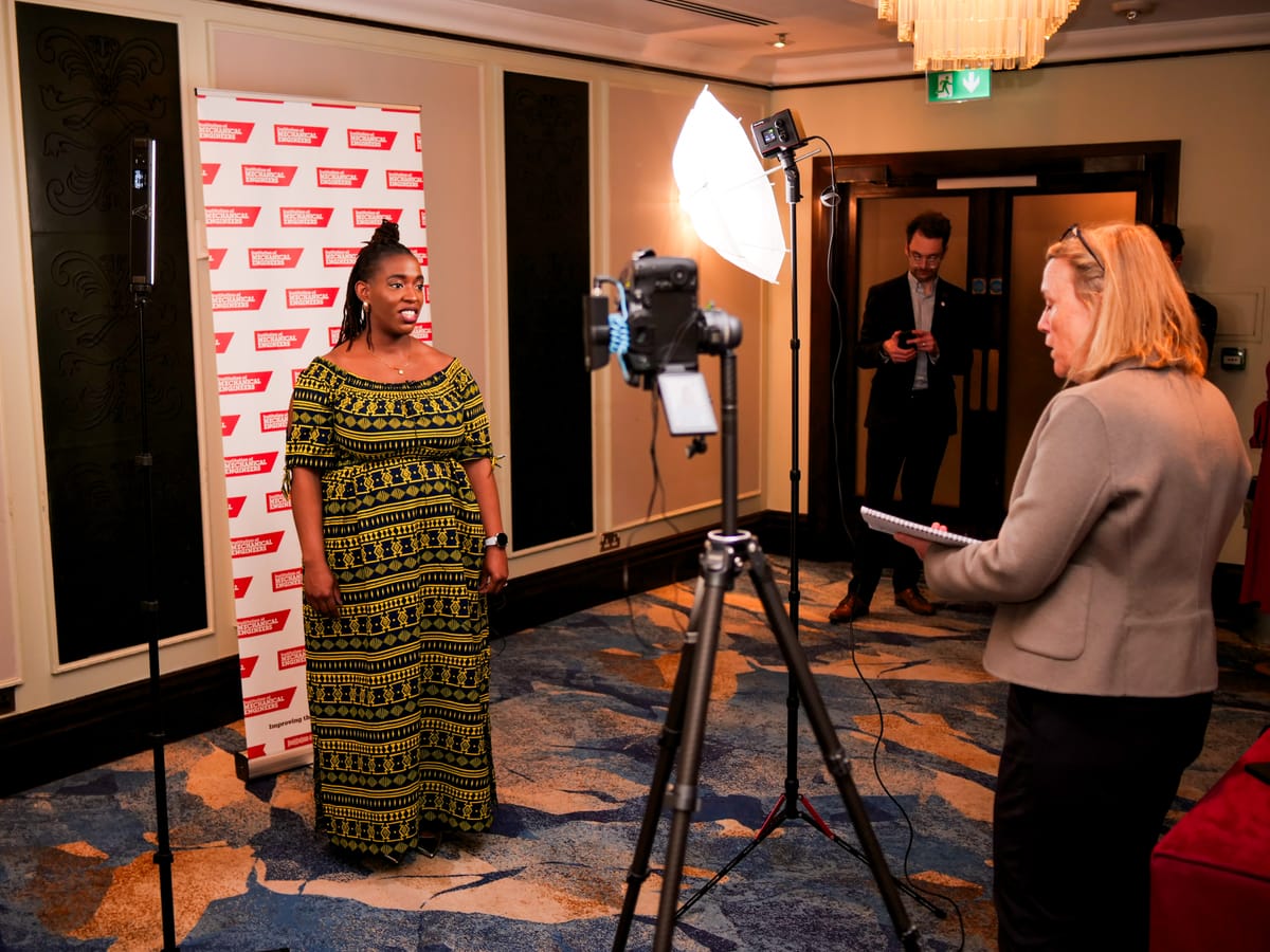 Filming an interview against a branded step-and-repeat backdrop at a corporate event.
